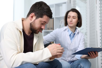 Photo of Alcoholic man having appointment with healthcare specialist in clinic. Addiction treatment