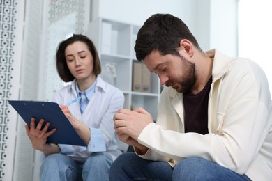 Photo of Alcoholic man having appointment with healthcare specialist in clinic. Addiction treatment