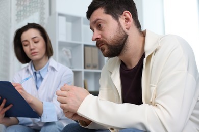 Photo of Alcoholic man having appointment with healthcare specialist in clinic. Addiction treatment