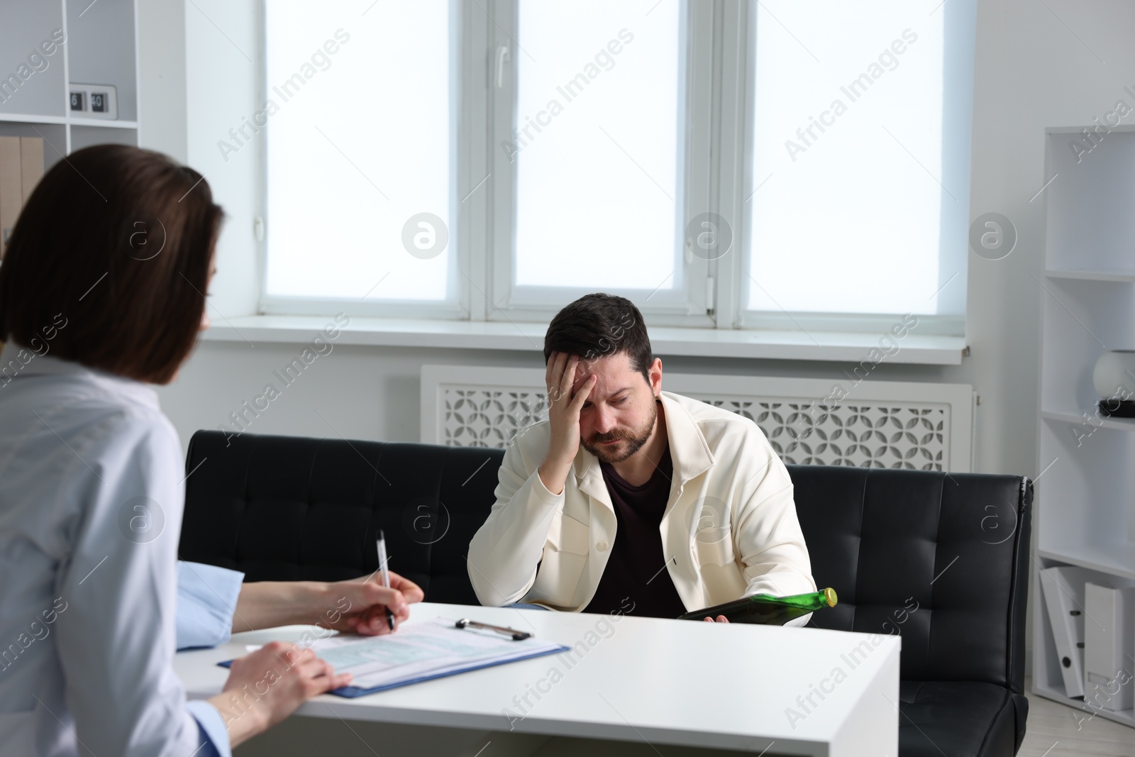 Photo of Alcoholic man having appointment with healthcare specialist in clinic. Addiction treatment