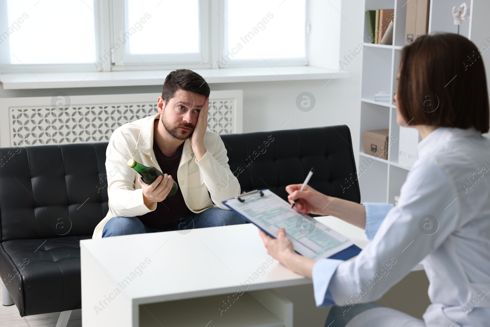 Photo of Alcoholic man having appointment with healthcare specialist in clinic. Addiction treatment