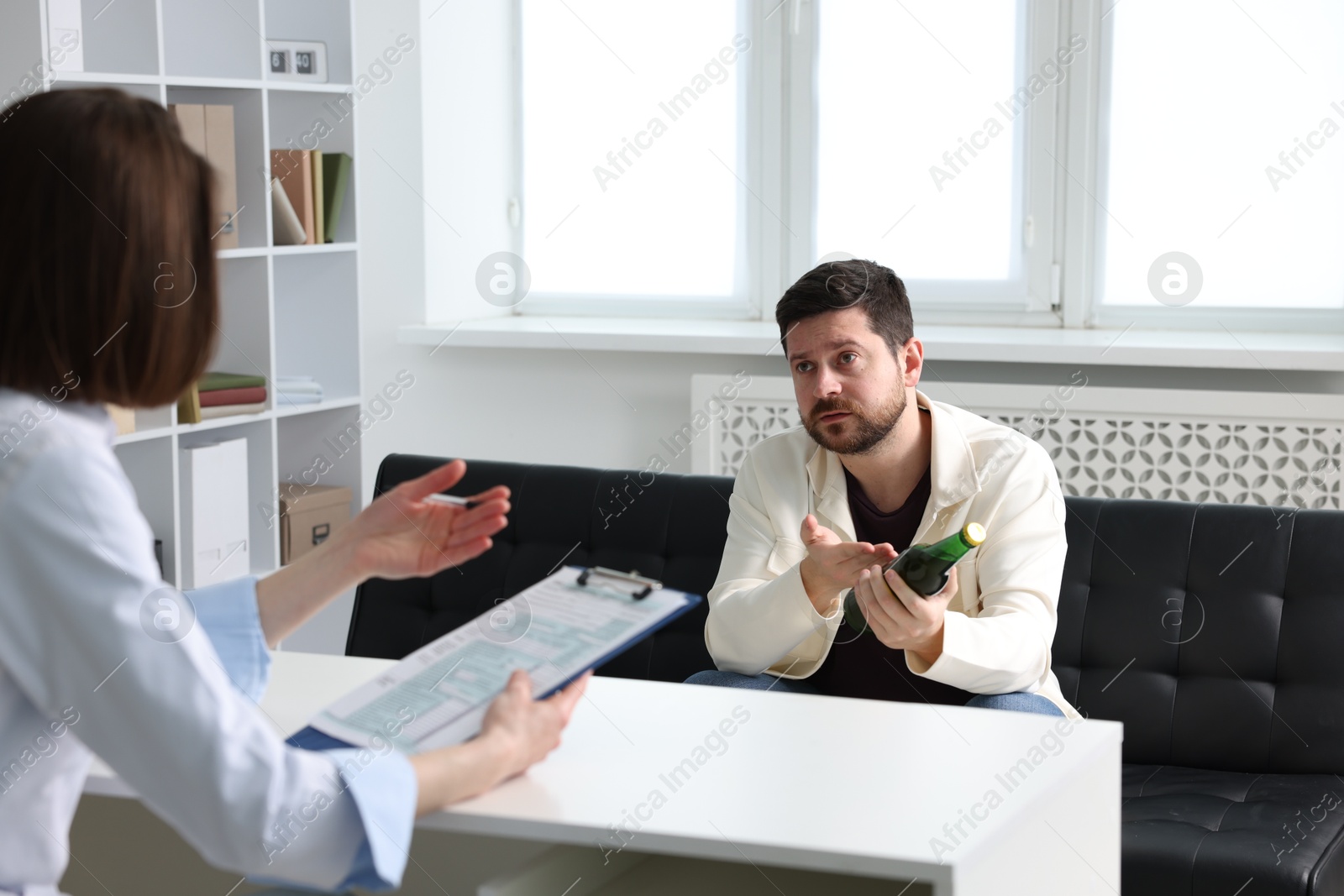 Photo of Alcoholic man having appointment with healthcare specialist in clinic. Addiction treatment