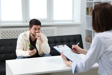 Photo of Alcoholic man having appointment with healthcare specialist in clinic. Addiction treatment