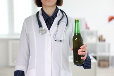 Photo of Healthcare specialist with bottle of beer in clinic, closeup. Addiction treatment