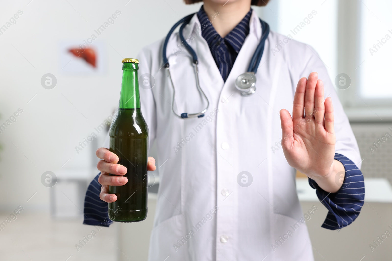 Photo of Healthcare specialist with bottle of beer showing stop gesture in clinic, closeup. Addiction treatment