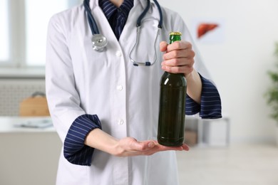 Photo of Healthcare specialist with bottle of beer in clinic, closeup. Addiction treatment