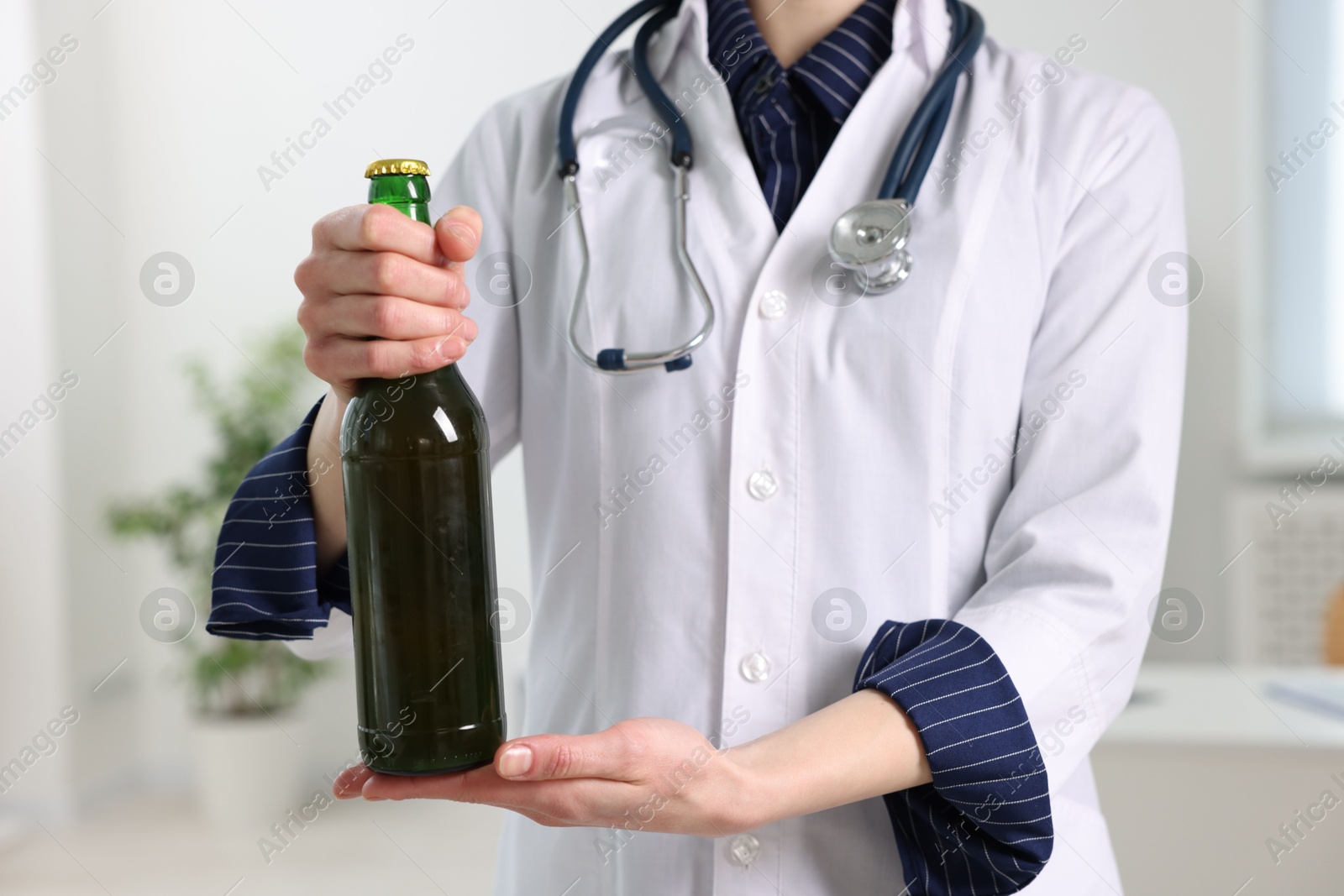 Photo of Healthcare specialist with bottle of beer in clinic, closeup. Addiction treatment