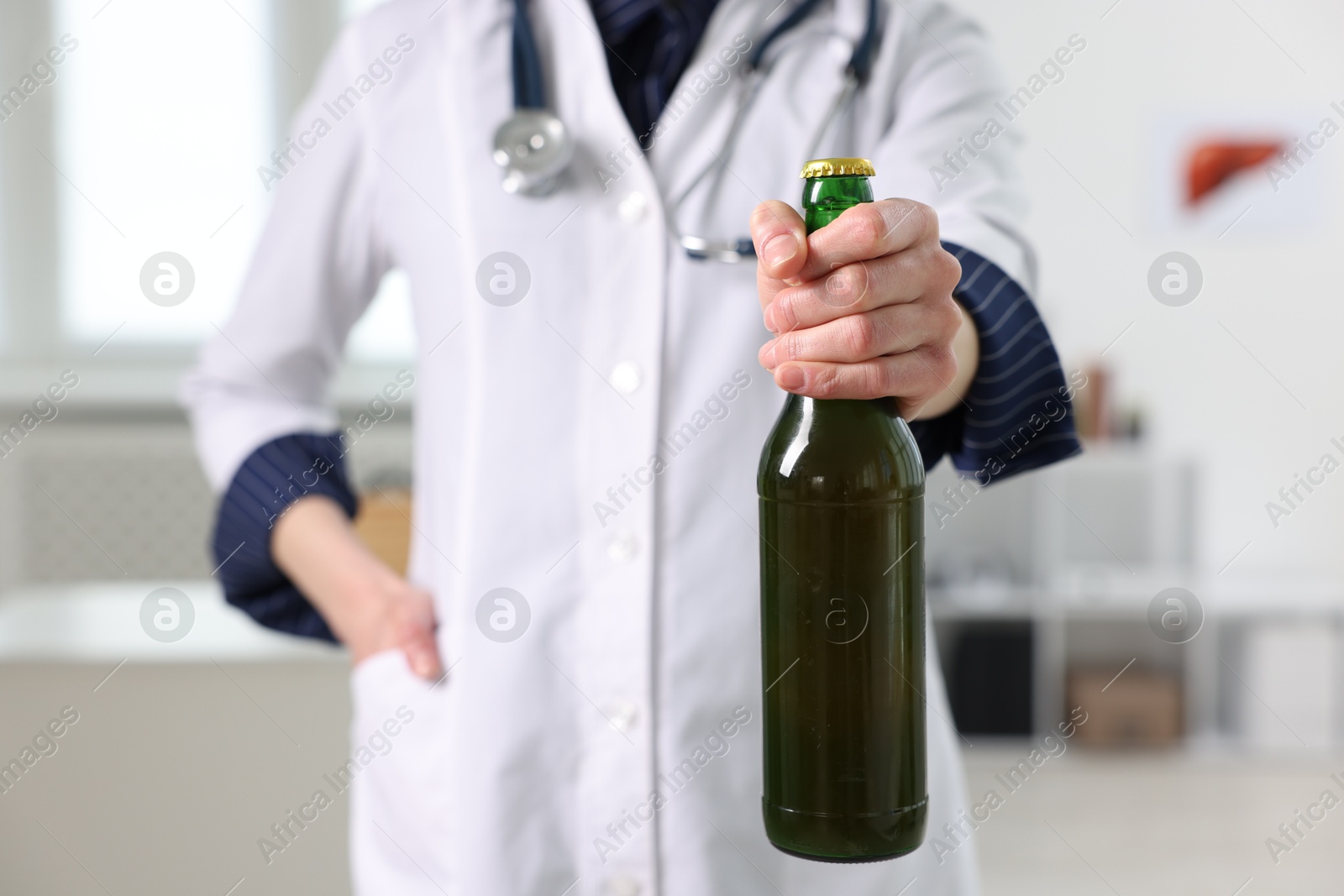 Photo of Healthcare specialist with bottle of beer in clinic, closeup. Addiction treatment