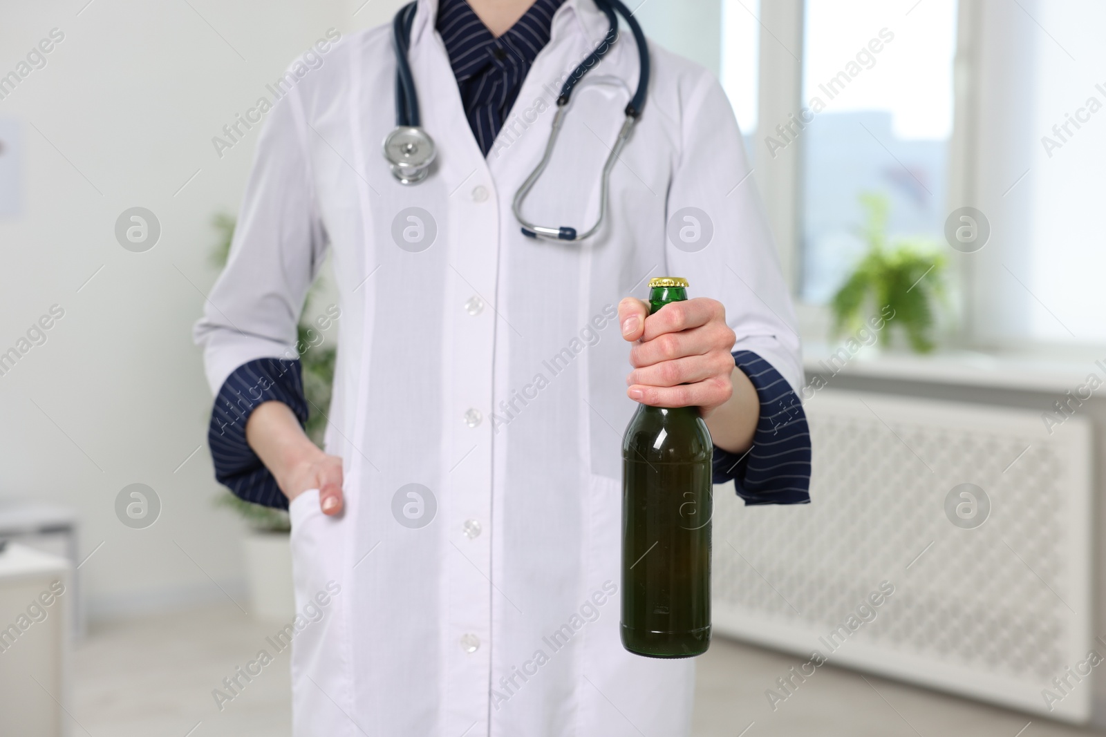 Photo of Healthcare specialist with bottle of beer in clinic, closeup. Addiction treatment