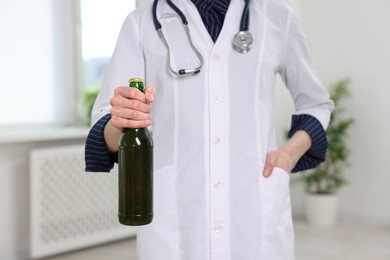 Photo of Healthcare specialist with bottle of beer in clinic, closeup. Addiction treatment