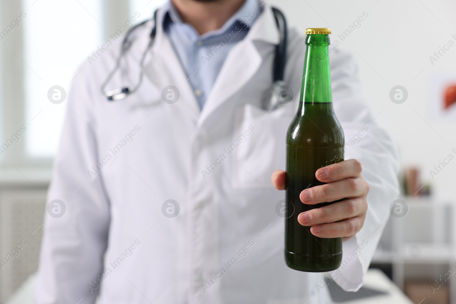 Photo of Healthcare specialist with bottle of beer in clinic, closeup. Addiction treatment