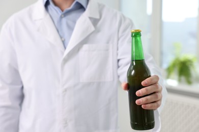 Photo of Healthcare specialist with bottle of beer in clinic, closeup. Addiction treatment