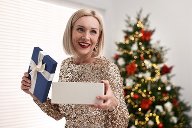 Photo of Smiling woman with perfect makeup and Christmas gift at home. Space for text