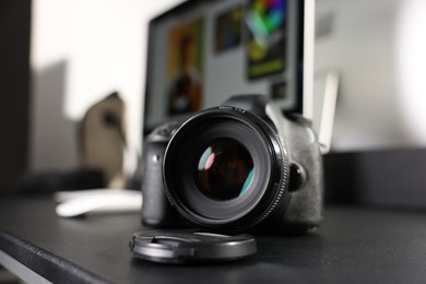 Photo of Professional camera and computer on black desk indoors, selective focus