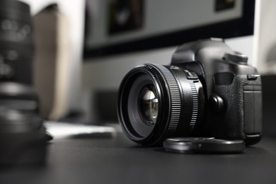 Photo of Professional camera, lens and computer on black desk indoors, selective focus