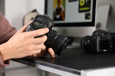 Photo of Photographer with professional camera at black desk indoors, closeup