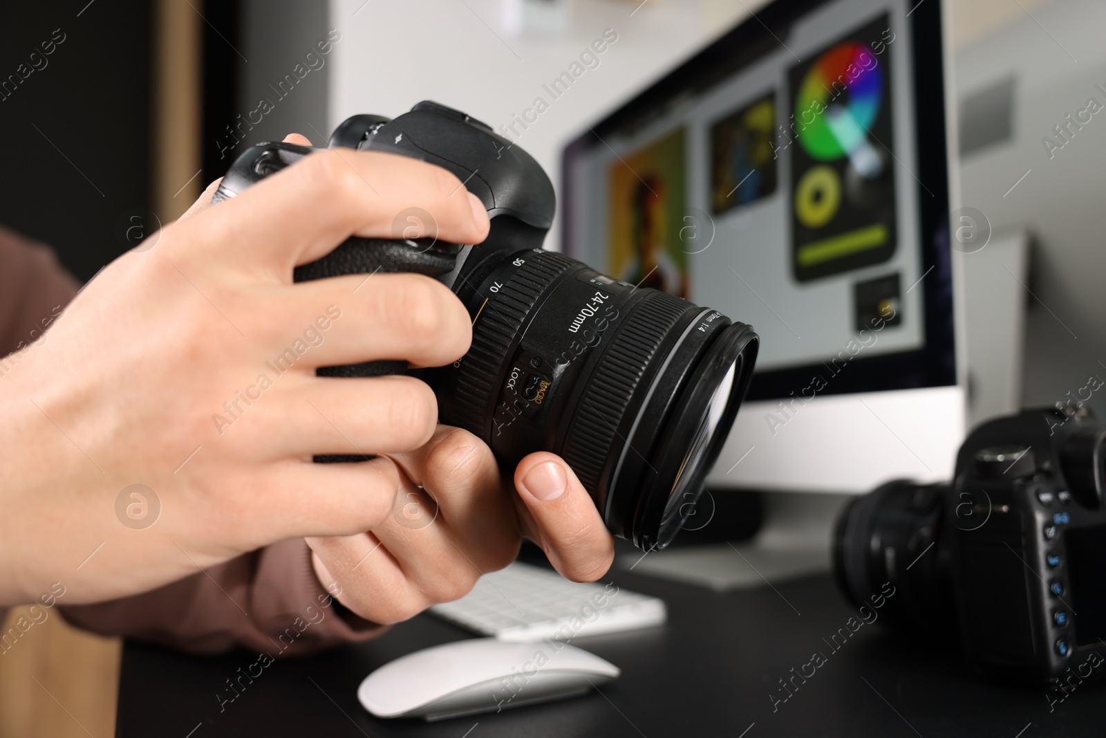 Photo of Photographer with professional camera at black desk indoors, closeup