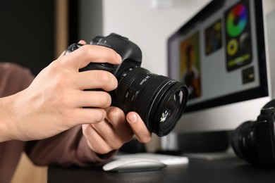 Photo of Photographer with professional camera at black desk indoors, closeup