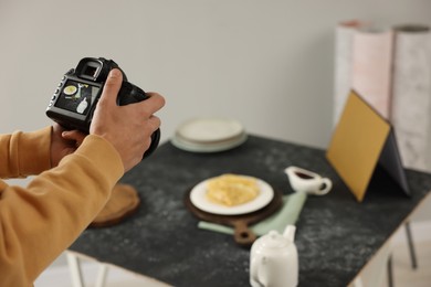 Photo of Man taking photo of crepes with professional camera in studio, closeup. Selective focus