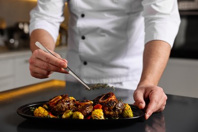 Photo of Professional chef serving dish at table indoors, closeup