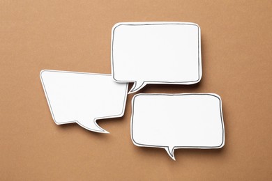 Photo of Blank speech bubbles on brown background, top view. Space for text