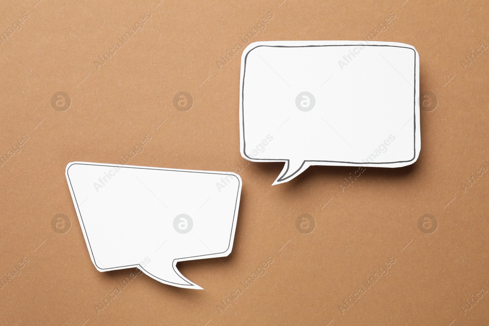 Photo of Blank speech bubbles on brown background, top view. Space for text