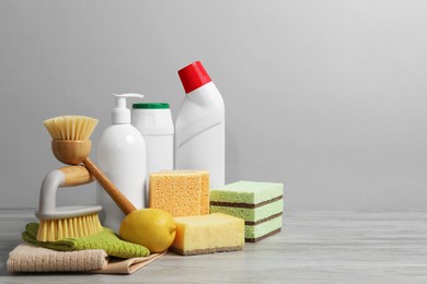 Photo of Eco-friendly cleaning products and supplies on wooden table against grey background, space for text