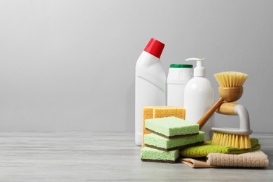 Photo of Eco-friendly cleaning products and supplies on wooden table against grey background, space for text