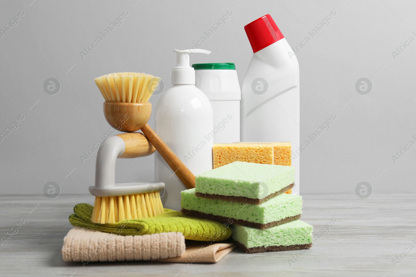 Photo of Eco-friendly cleaning products and supplies on wooden table against grey background