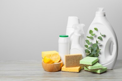 Photo of Eco-friendly cleaning products, supplies and eucalyptus branches on wooden table, space for text