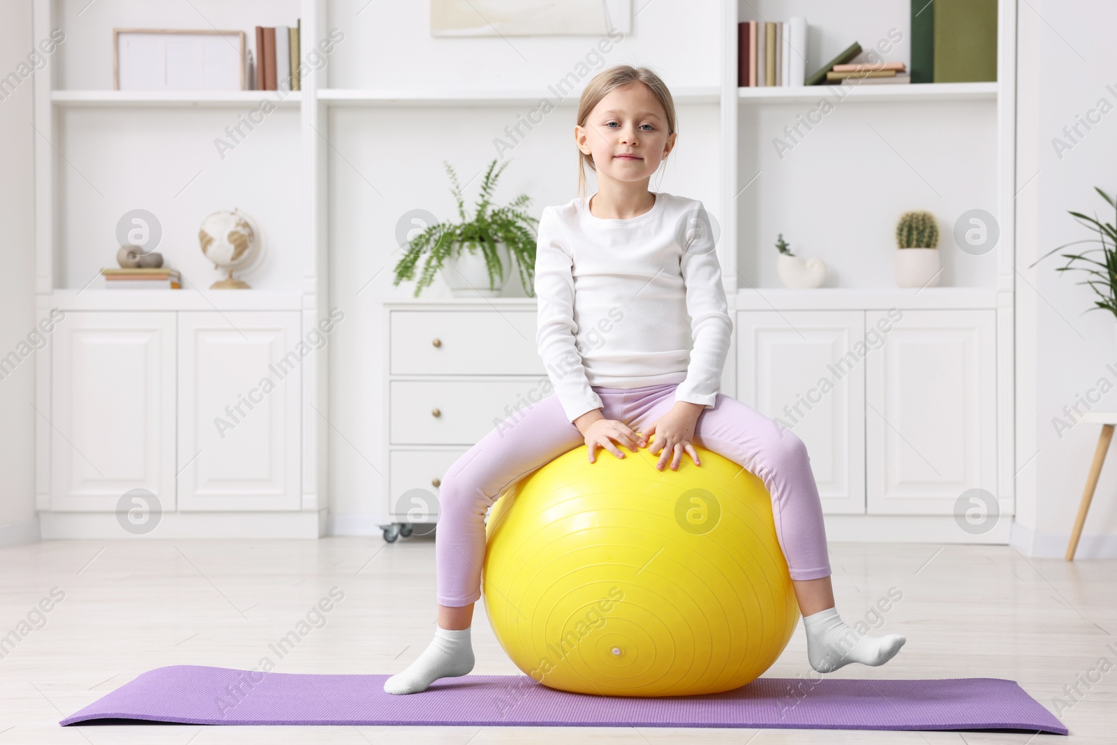 Photo of Cute little girl with fitness ball indoors, space for text