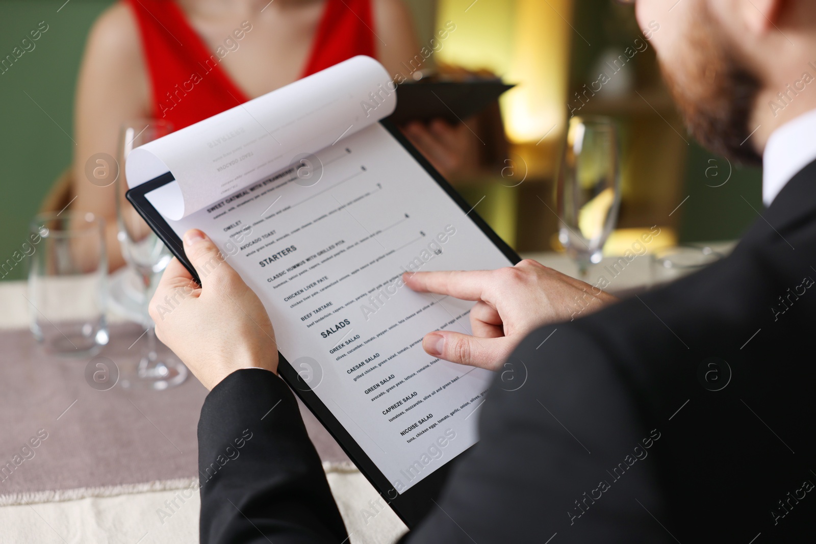 Photo of Couple choosing dishes from menu at table in restaurant, closeup