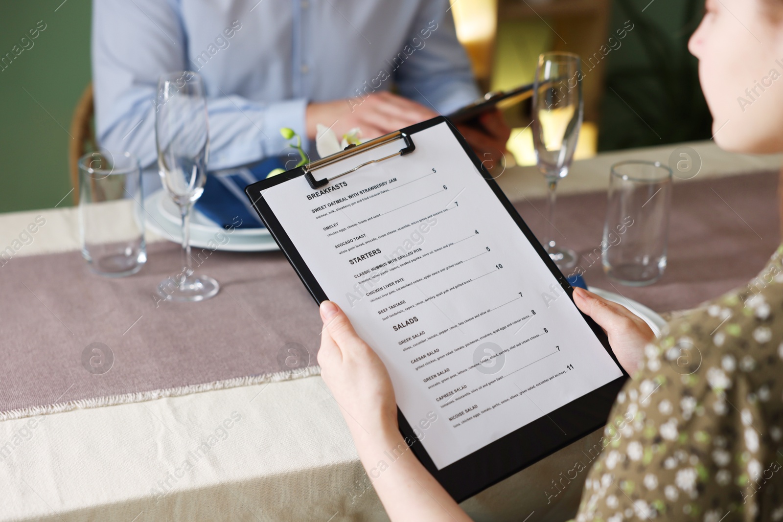 Photo of Couple choosing dishes from menu at table in restaurant, closeup