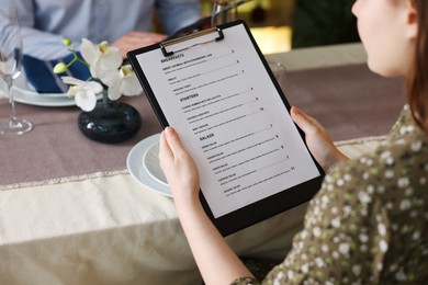 Photo of Couple choosing dishes from menu at table in restaurant, closeup