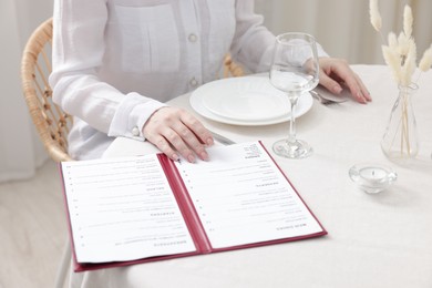 Photo of Woman with menu at table in restaurant, closeup