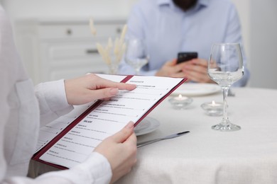 Photo of Woman with menu at table in restaurant, closeup