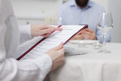 Photo of Woman with menu at table in restaurant, closeup