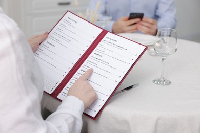 Photo of Woman with menu at table in restaurant, closeup