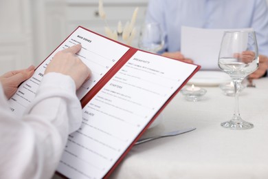 Photo of Woman with menu at table in restaurant, closeup