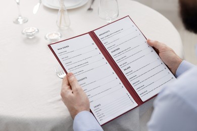 Photo of Man with menu at table in restaurant, closeup