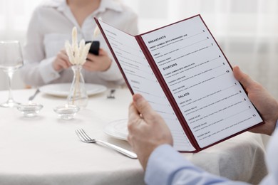 Photo of Man with menu at table in restaurant, closeup