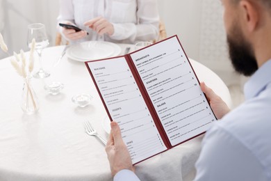 Photo of Man with menu at table in restaurant, closeup