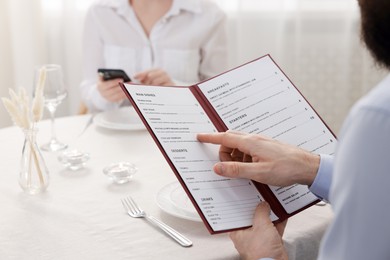 Photo of Man with menu at table in restaurant, closeup