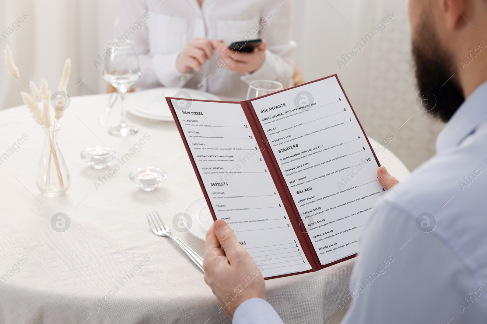 Photo of Man with menu at table in restaurant, closeup