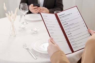 Photo of Woman with menu at table in restaurant, closeup