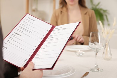 Photo of Man with menu at table in restaurant, closeup