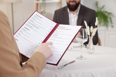 Photo of Woman with menu at table in restaurant, closeup