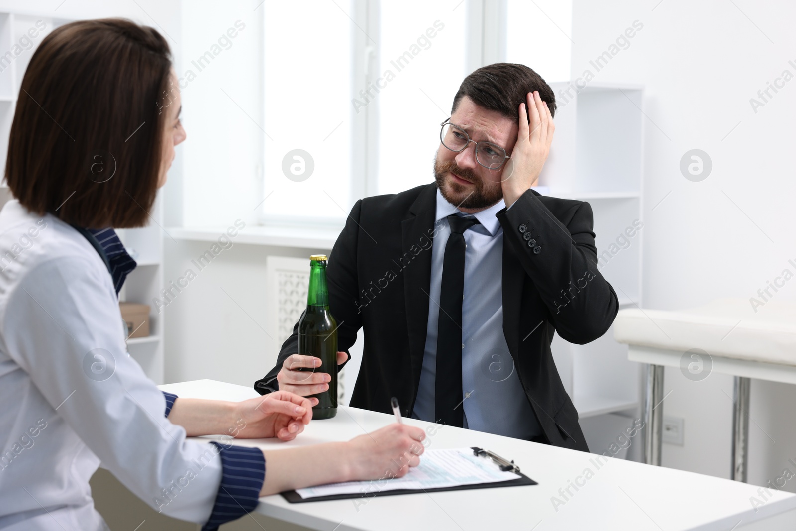 Photo of Alcoholic man having appointment with healthcare specialist in clinic. Addiction treatment