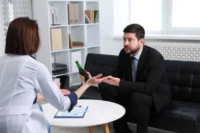 Photo of Alcoholic man having appointment with healthcare specialist in clinic. Addiction treatment