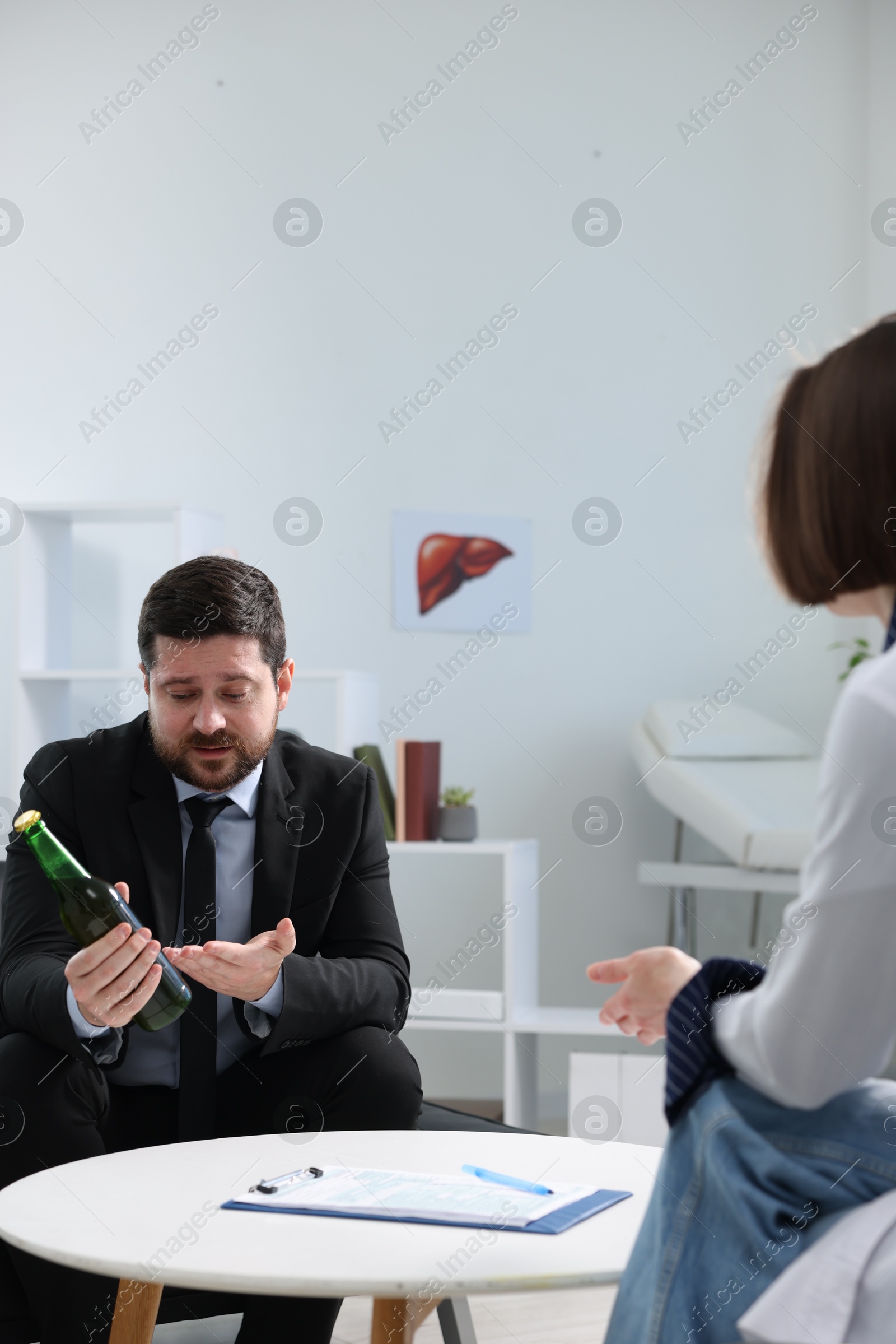 Photo of Alcoholic man having appointment with healthcare specialist in clinic. Addiction treatment